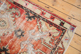 Corner of distressed vintage Oushak runner featuring ivory spandrel and black serpent motif border.
