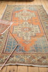 Decorative distressed vintage Oushak rug, low pile texture with faded tangerine and blue floral motifs.