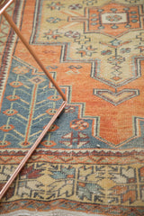 Distressed Oushak rug corner detail with faded tangerine and slate blue plant motifs.