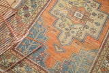Distressed vintage Oushak rug with low pile, tangerine, slate blue, and sand geometric spandrels.