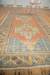 Distressed Oushak rug corner, faded tangerine field, slate blue germinating plants, low pile.