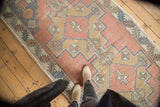 Distressed Oushak runner, dusty rose geometric medallion, stepped spandrels, serrated leaf border.