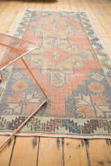Geometric medallions and serrated leaf border detail on this distressed Oushak rug runner.