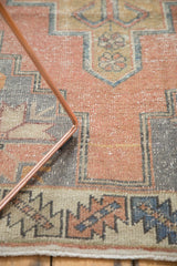 Distressed Oushak runner with dusty rose field, slate blue geometric border, and original selvage.