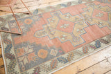 Distressed dusty rose Oushak runner with slate blue geometric spandrel and serrated leaf border.