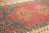 Distressed vintage Oushak rug corner showing geometric stepped patterns in red, blue, gold.