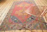 Vintage distressed Oushak rug corner with visible knot heads and muted floral border.
