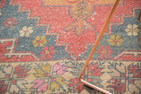 Distressed textured Oushak rug showcasing cranberry red and slate blue primitive motifs.