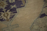Hand-knotted Oushak rug detail: open ivory field, stylized charcoal, teal, and bronze motifs.