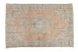 Distressed vintage Oushak carpet, tangerine orange field with faded blue floral medallion.