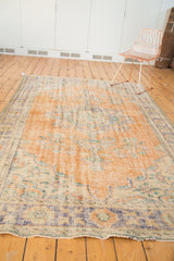 Distressed end of vintage Oushak rug with faded royal blue border and visible wear.