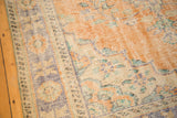 Distressed Oushak carpet texture with worn knot heads, exposed foundation, tangerine, and ivory.