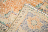 Distressed vintage Oushak rug texture, showing short tangerine pile, exposed foundation, knotted back.