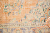 Distressed texture of vintage Oushak carpet with worn knot heads in orange, ivory, and blue.