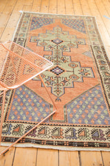 Distressed geometric border and muted apricot, inky blue, celadon patterns of a vintage Oushak runner.