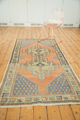Geometric boteh corner spandrel of a distressed Oushak runner, in pale apricot, blue, and celadon green.