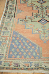 Detail of distressed Oushak rug: pale apricot field, blue boteh corner spandrel, celadon geometric patterns.