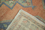 Distressed apricot Oushak runner pile, showing geometric blue and green patterns, reverse weave, and selvage.