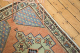 Geometric border details of a distressed vintage Turkish Oushak rug in apricot, celadon, and blue.