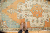 Stepped spandrel design in pale aqua blue and burnt orange on a distressed Oushak rug.