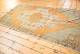 Distressed Oushak rug corner detail with stepped drawing, faded aqua, and antique ivory tones.