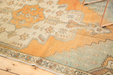 Stepped aqua spandrel and faded burnt orange field on a distressed Oushak rug.