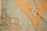 Distressed Oushak rug with stepped geometric corner spandrel in faded aqua and gold.