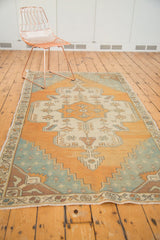 Faded aqua blue and burnt orange distressed Oushak rug corner with aubergine spandrels.