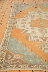 Textured corner of distressed Oushak rug, showing stepped spandrel in faded aqua and burnt orange.