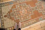 Distressed vintage Oushak runner rug with bronze, teal, copper floral motifs and textural wear.