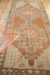 Detail of the vintage distressed Oushak runner's bronze and teal floral medallion pattern.