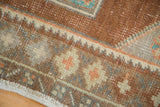 Distressed vintage Oushak rug texture showing bronze, copper, and teal floral blossoms.