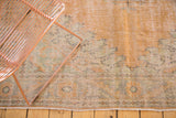 Distressed Oushak rug with worn texture, apricot, pale green, and charcoal floral vinery near fringe.