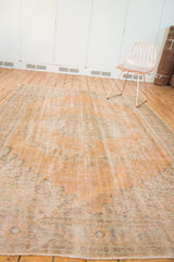 Distressed vintage Oushak rug surface, with apricot hues and visible foundation.