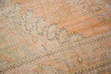 Close-up of the distressed Oushak pile texture, showing apricot, pale sea foam green, and faded charcoal patterns.