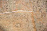 Distressed Oushak rug corner showing worn knot heads, visible foundation, and secured edge.