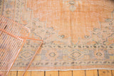 Distressed apricot Oushak carpet with softened pile, revealing muted blue and green patterns.
