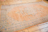 Distressed Oushak rug corner, apricot field with faded blue border and lazy lines.