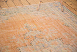Textured distressed apricot field with faded pale blue and green floral patterns.