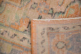 Distressed Oushak rug's pile texture, vibrant apricot selvedge, and woven foundation.