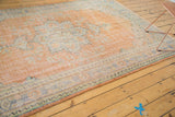 Distressed apricot field with faded blue and mint green patterns on a vintage Oushak rug corner.