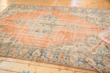 Distressed vintage Oushak rug detail with faded apricot peach field and royal blue border.