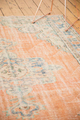 Distressed texture of vintage Oushak rug, showing apricot peach field with faded blue floral motifs.