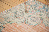 Distressed Oushak rug border showcasing soft apricot and blue geometric patterns with worn texture.