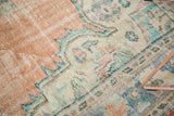 Distressed Oushak rug pile texture with apricot, mint, and faded blue patterns.