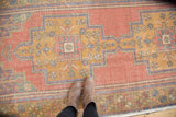 Distressed vintage Oushak rug section with cinnabar red and dusty gold geometric floral patterns.