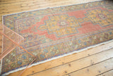 Distressed Oushak runner's textured pile, highlighting soft floral patterns and rich hues.