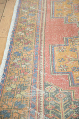 Decorative distressed Oushak runner edge showcasing faded cinnabar red and dusty gold with blue patterns.