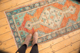 Vintage distressed Oushak rug with textured burnt orange field and mint green corner motifs.