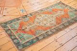 Distressed burnt orange field with faded ink blue border motifs on vintage Oushak rug.